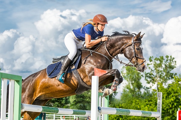 Female equestrian jumping over an obstacle in competition